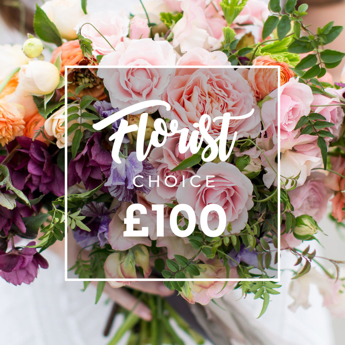 A lush, hand-tied bouquet is pictured close-up, the kind of arrangement Flower Delivery North Watford crafts for special moments across North Watford - from Cassiobury Park picnics to thoughtful deliveries along Watford High Street. Dominant pale-pink garden roses with their full, ruffled faces form the visual heart, surrounded by rich plum or burgundy hellebore-like flowers that add depth and a slightly moody counterpoint. Interspersed delicate sweet peas in striped lavender-and-white bring a vintage, scented softness, while peach and coral ranunculus offer layered richness and a satiny texture. Creamy whites and small filler blooms lift the palette, and varied greenery - slender vines, eucalyptus-like leaves and broader glossy foliage - creates a loose, natural silhouette that feels freshly gathered. A white rectangular overlay sits centrally on the image, the elegant script declaring Florist Choice, with smaller block CHOICE beneath and the bold price ?100 displayed clearly, communicating a florist-selected bouquet at this price point. The stems are gently held by visible hands at the bouquet's base, a pale sleeve blurred in the background that suggests careful hand-finishing rather than industrial assembly. The lighting is soft and flattering, highlighting petal texture and the gentle shadows between layers, conveying a sense of craft, fragrance and seasonal selection. This photograph reads as a luxurious yet unfussy gift option - perfect for anniversaries, birthdays, or to express sympathy - and reflects the local floristry sensibility of thoughtful, seasonal combinations delivered across the Vicarage Road and Watford Junction area.