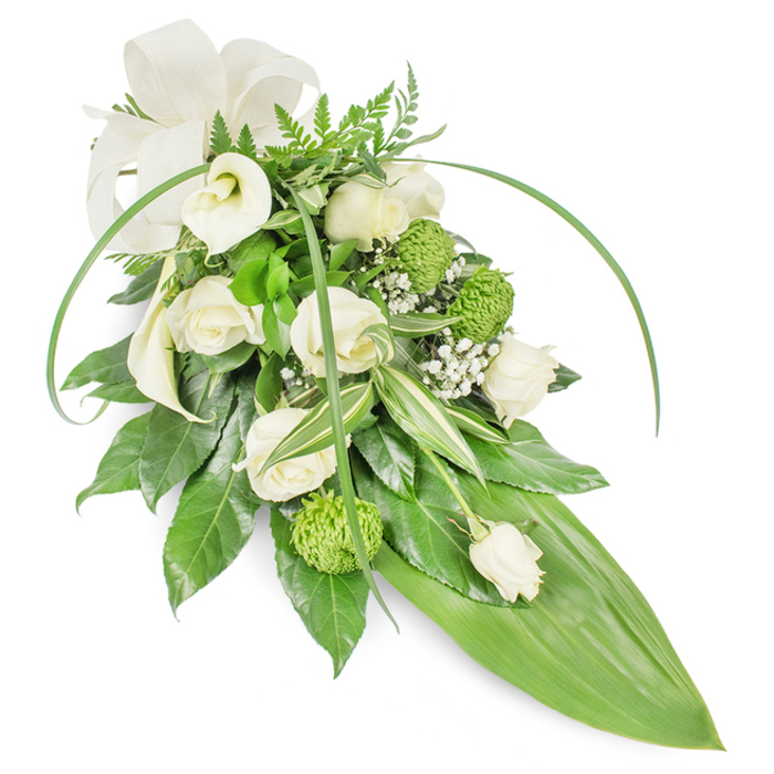 An elegant, elongated memorial spray arranged in serene whites and verdant greens sits photographed against a clean studio white, the lighting soft and shadowless to emphasize texture. Creamy white roses in varied stages of bloom form the heart of the design, their petals layered and tactile, while two white Calla lilies lift the gaze with their refined, trumpet-shaped curves. Bright lime-green button chrysanthemums appear as clustered, textured spheres, offering an arresting contrast to the roses' smooth curves. Sprays of delicate baby's breath (Gypsophila) are woven through the blooms, creating a misty, weightless veil that tempers the composition and invites quiet reflection. The greenery anchors the work: rich, glossy leaves create a compact base; lighter, variegated foliage with green-and-white striping adds depth; feathery fern fronds provide an airy crown; and long, sinuous blades of bright green foliage sweep over the sides to introduce rhythm and contemporary line. The design narrows to a prominent, bright green tropical leaf forming a polished, pointed tail, and an off-white, textured fabric bow at the upper left lends a formal, comforting accent. Texturally the piece moves from velvet to gloss to feathery lightness, and the sensory impression is understated - a soft rose perfume with fresh green notes. Intended as a respectful funeral or memorial tribute, this spray is a quiet, composed expression of remembrance, suitable for placing at local services, gravesides, or private vigils served by florists across North Watford and surrounding neighbourhoods.
