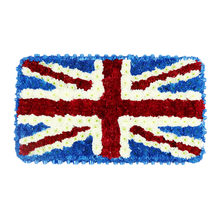 A solemn floral artwork in the shape of a horizontal rectangle portrays the Union Jack with striking accuracy, crafted entirely from tightly packed red, white, and blue flowers. The arrangement rests against a simple white backdrop, which allows every detail of the design to stand out, much as a carefully folded flag might draw the eye during a service at a local North Watford chapel. Deep blue blooms, most likely compact hydrangeas or spray chrysanthemums, fill the background and create a consistent frame along all four edges, giving the piece a stable, grounded feel. Over this dense cushion of blue, the bold red St. George's Cross stretches from top to bottom and side to side, its arms rendered from vivid red flowers whose layered petals add a subtle sense of movement and depth. The diagonal red lines of St. Patrick's Cross are equally precise, threading across the flag and meeting at the centre with careful, measured spacing. Clean white blooms form the broad diagonals of St. Andrew's Cross and the narrow separating lines around the red crosses, echoing chalk-bright paths and winter skies over nearby parks and streets in North Watford. Seen close up, the tribute feels almost three-dimensional, with each tiny flower head contributing to a soft, pillowy surface that invites touch, even in a moment of grief. The overall tone is reverent and patriotic, suited to ceremonies for veterans, public servants, or anyone whose life was closely tied to British traditions. Whether placed beside a coffin, at a memorial near St Albans Road, or at a graveside, this handcrafted Union Jack tribute quietly conveys respect, gratitude, and unity.