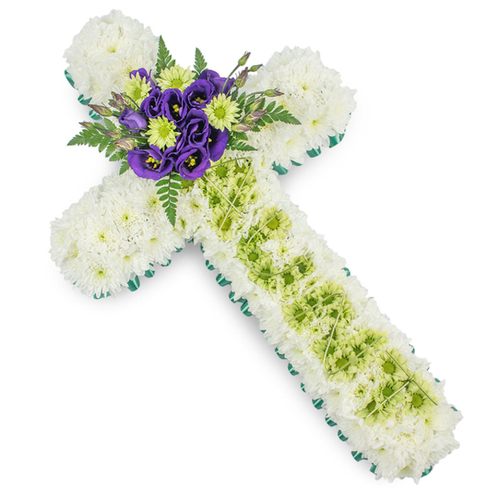 A thoughtfully arranged floral cross tribute is shown in full, set against an uncluttered white background so every petal and leaf stands out clearly, much like a carefully tended memorial in a North Watford churchyard. The cross's body is almost entirely composed of small, pure white spray chrysanthemums, so densely placed that they form a continuous, cushion-like surface. Their fine petals, each slightly curved and feathery, create a soft texture that suggests comfort and peace. Running precisely around the perimeter of the cross is a band of vibrant green, most likely a satin ribbon or leaf trim, which crisply outlines the arms and base, adding structure and a modern touch to this traditional symbol of faith. Down the centre of the vertical arm sits a narrow, inset panel of lime green chrysanthemums or button mums. These rounded, fresh green blooms introduce light and vitality, their colour reminiscent of new spring growth. Over this green inset, fine, pale green wires or decorative strands are laid in a delicate criss-cross pattern, adding a subtle, almost geometric layer of interest. At the very centre, where the horizontal and vertical arms meet, a focal posy draws attention. Deep, royal purple Eustoma (Lisianthus) flowers, with their slightly ruffled, velvety petals, are nestled among crisp lime green blooms, framed by graceful fern fronds that extend outward and add depth and natural movement. The composition feels balanced and composed, ideal for a Christian funeral service, crematorium farewell, or graveside tribute in North Watford. It quietly conveys sympathy, eternal rest, and the comfort of shared faith for families gathering to say goodbye.