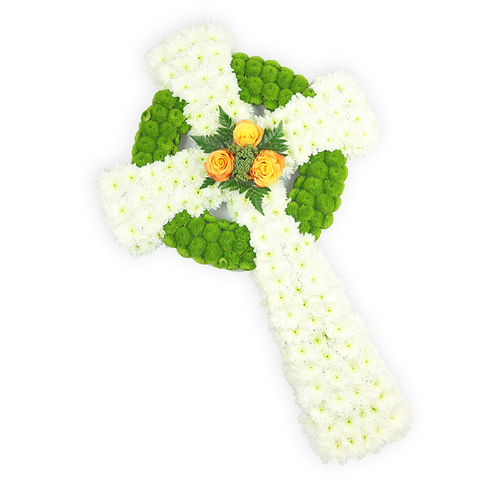 Presented against a luminous white background and photographed from a soft elevated viewpoint, this floral Celtic cross is a study in contrast and calm. The main body is composed of compact white spray chrysanthemums whose clustered blooms form a dense, velvety surface that reads as purity and gentle solemnity. Interspersed within this white field are striking bands and a defining circular ring of apple-green button chrysanthemums; their small, rounded heads create an almost beaded texture that outlines the cross's knot-like centre and alternates along the horizontal arms, lending the piece a sculptural rhythm. At the precise meeting point of the arms, three bright orange-yellow roses are arranged as a luminous focal cluster - their layered petals unfurling like tiny suns against the cool backdrop, framed by slender, dark green fern or foliage sprigs that provide contrast and a whisper of woodland scent. The lighting is soft yet clear, accentuating petal contours and the three-dimensional form so the memorial reads with dignity and clarity. This arrangement feels particularly fitting for funeral chapels and graveside remembrances across North Watford and neighbouring Leavesden, where families often ask for pieces that honour Irish roots or the Celtic emblem. The overall effect is respectful and eloquent: a floral tribute that balances tradition with contemporary simplicity, offering comfort through texture, colour, and careful floral craft.