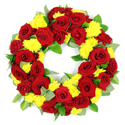 This photograph shows a beautifully balanced circular funeral wreath, set against a stark white background so that every flower and shade of green is clearly defined. The ring is built around an abundance of deep red roses, their velvety petals unfurling in layered spirals from bright crimson at the tips to velvety, wine-dark tones near the centre. They are interwoven with generous clusters of bright yellow chrysanthemums, whose many fine, feathery petals create a soft, cushion-like texture that contrasts with the smoothness of the rose blooms. The red and yellow flowers repeat all the way around the circle, giving an impression of steady rhythm and harmony, much like the quiet flow of daily life around North Watford's residential streets. Behind and between the blossoms, rich green foliage forms a supportive frame, filling the wreath without overwhelming it. Broad, glossy leaves, probably salal or ruscus, sit beside subtler grey-green sprigs reminiscent of eucalyptus, adding both depth and a slightly wild, natural character. The flowers are tightly packed, leaving no gaps, and the circular shape remains perfectly even, with a clear centre that symbolises eternity and ongoing remembrance. Illuminated by bright, even lighting, the colours appear vivid and true, while the textures of each petal and leaf are easy to imagine under the fingertips. The overall feeling is one of compassionate reflection: a dignified floral tribute that would be fitting for a funeral, crematorium service, or graveside ceremony in and around North Watford, offering both comfort and a quiet celebration of a loved one's life.