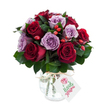 A lush, rounded bouquet of fully opened roses, arranged with the intimacy of a hand-tied gift and set against a pristine white background so every shade reads clearly. Deep crimson and rich burgundy roses form the warm core, their velvety petals unfurling in layered spirals; threaded through these are softer lavender and dusty lilac roses whose cooler tones soften the composition and lend a quiet, romantic counterpoint. Dark green foliage - glossy Ruscus or Salal - nests the blooms, its firm leaves creating pockets of shadow and depth that make the reds glow more intensely. Scattered among the roses are small, bright red-orange rose hips, their smooth, rounded skins adding a rustic, autumnal punctuation that contrasts with the roses' satin texture. The flowers sit in an antique-style mercury glass vase, silvered and slightly mottled so it shimmers without overpowering the blooms; the vase's bulbous base tapers to a narrower neck, where a length of natural raffia or twine is tied in a simple bow. A small rectangular white tag hangs forward from the neck, bearing a delicate hand-drawn rose illustration and space for a short message, hinting at a thoughtful gift inside. Under soft studio light the petals show subtle variations - duskier edges, paler centers - and a faint green warmth from the foliage suggests the scent of freshly cut stems. This is a bouquet that reads as both luxurious and sincere, suited to anniversaries, quiet celebrations, or as a comforting surprise for someone local to North Watford, evoking strolls through nearby Cassiobury Park and the gentle kindness of giving flowers by hand.