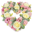 A softly coloured, heart-shaped wreath of sympathy flowers stands out clearly against a bright white background, its contours perfectly defined by layers of pastel blooms and cool foliage. The heart is densely packed from edge to edge, giving it a plush, almost cushion-like appearance that radiates warmth and care. Cream and light yellow roses are placed as the main focal blooms, their velvety petals spiralling into generous, rounded flowers that suggest devotion and respect. Around them, clusters of light pink carnations add a delicate, frilled texture, each small petal catching the light and creating gentle shadows that enrich the overall design. Threads of deeper pink and mauve lisianthus wind through the arrangement, their softer, more open petals bringing depth and a quietly romantic note to the tribute. Silvery eucalyptus leaves weave in amongst the flowers, their round shapes and muted green tones providing a calm contrast and helping to trace the outline of the heart. Small yellow-green buds are tucked here and there, tiny hints of new life and continuity that offer a whisper of hope amid sorrow. The composition feels carefully considered yet natural, like a loving farewell put together by a family who knows the peaceful corners of North Watford-perhaps remembering walks along local streets and parks. This heart-shaped floral tribute is ideally suited for funerals, memorials, or anniversary remembrances, and would be a fitting choice for delivery to local chapels and crematoria. It communicates sympathy, compassion, and cherished memories through its gentle colours and expertly crafted form.