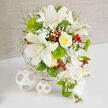 On a clean white tabletop against a softly textured beige wall, this elegant bouquet appears like a still-life painting styled for a North Watford wedding suite. The composition is dominated by crisp white Oriental lilies, their generous petals fully unfurled and dusted with faint speckles, each bloom revealing tall stamens that add structure and depth. Tucked among them is a flawless yellow rose, tightly swirled at its centre and gradually loosening into creamy, sunlit petals that bring warmth to the cool palette. Clusters of airy white baby's breath form a cloud-like veil between the larger flowers, giving the whole design a gentle, romantic softness reminiscent of morning mist over Callowland recreation ground. Bright green, cushiony Green Trick dianthus sit like miniature moss balls, their vivid colour and unusual texture creating a modern contrast to the smoothness of the lilies and rose. Fine, feathery foliage and delicate green stems weave through the composition, adding lightness and a natural, garden-picked feel. Here and there, glossy red hypericum berries glisten like tiny cherries, adding a cheerful, festive note that would suit winter weddings or stylish celebrations around North Watford. Flowing down the right-hand side, a refined cascade of white Phalaenopsis orchids trails gracefully, their petals smooth and satiny, some with a soft yellow glow at the centre, accompanied by fresh green buds that hint at blooms still to open. The flowers emerge from a white woven basket base, its texture subtly echoed by two decorative white wicker spheres resting on the table, as if a local stylist had finished setting a reception table in a nearby venue. This arrangement feels both contemporary and timeless, a luxurious centrepiece that would look at home at an intimate ceremony or elegant family gathering.