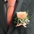 There's a sincere elegance in this classic North Watford buttonhole, designed to capture the fleeting beauty and anticipation of a celebration day. Central to the arrangement is a luminous rose in the gentlest peach tone, its petals unfurling with the soft sheen of morning light spilling over local gardens. Airy sprigs of white baby's breath cradle the rose, their tiny blossoms lending a frothy texture-a nod to dew-laden lawns and the renewal they promise. Wisps of verdant foliage, possibly ruscus or fern, arc gracefully around the bloom, contributing a sense of freshness and local authenticity. All of this is set against the structured dark grey lapel of an immaculately tailored suit, anchored by a peach satin ribbon that ties the entire composition in polished harmony, echoing the matching necktie beneath. The fragrance of the buttonhole is subtle, evoking hints of springtime in North Watford's quiet corners-inviting memories and softly brimming with joy. Crafted by attentive local florists, this boutonniere is more than an accessory; it is a keepsake designed to rest at the heart of Watford's most cherished moments, available for personal delivery to homes and venues across the neighbourhood.