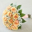 Lovingly arranged for a special Watford occasion, this bridal bouquet blends romance with quietly confident beauty. Nestled tightly together, twelve roses in peach and apricot hues spiral open, their petals emitting a gentle, golden glow-much like the soft sunset that bathes North Watford's leafy streets. Enveloping the roses is a filigree of white baby's breath, offering a lace-like delicacy that lightens the mood and adds a touch of ethereal grace. Sprigs of glossy, dark green foliage-selected with an eye to freshness and form-provide depth, framing the blooms and suggesting the lush woodlands around Cassiobury. Finished with a charming, wide peach ribbon around the stems, its surface accented by neatly set pearls, the handle invites touch, cool and smooth in the hand. The scent is understated, with notes of sweet roses and crisp greenery-evocative of a quiet morning walk in the parks near North Watford. In every aspect, from the balanced colours to the impeccable wrapping, this bouquet is designed to accompany treasured vows, heartfelt celebrations, or new beginnings, embodying the quiet joy and hope of the local community.