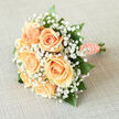 There is a quiet, deliberate grace to this bridal bouquet, a local florist's homage to classic romance crafted for weddings across North Watford. Six creamy-peach roses are gathered tightly at the heart, their petals turning outward in soft, luminous spirals that invite a gentle touch. Surrounding the roses, a frothy veil of white gypsophila breathes delicate texture into the silhouette-the tiny blooms catching and reflecting light like a fine mist. Deep emerald foliage threads through the composition, glossy and resilient, giving the pastel centre something to lean against so each flower sits with clarity and purpose. The stems are hand-wrapped in smooth peach satin, the ribbon neatly folded and secured, and a neat line of pearls runs along the handle, each pearl catching a glint of sunlight as if keeping a small, personal memory for the bride. As a Watford florist familiar with Vicarage Road afternoons and the quieter streets off Hempstead Road, I picture this bouquet carried down a village lane or presented at a small ceremony close to Watford Junction-its scent subtle and fresh, like a linen-dried breeze mingled with rose-sweetness. Prepared with careful proportions and an eye for how the bouquet reads in photos and in hand, this arrangement by Flower Delivery North Watford is meant to feel intimate and timeless: a compact, luminous cluster that balances softness with compositional poise for any spring or summer celebration.