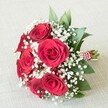 Laid gently across a pale, textured cloth-reminiscent of a vintage linen table near North Watford's Market Street-this stunning bouquet showcases approximately six deeply saturated red roses, each one open and velvet-soft, heliotropes of passionate romance. Among the rich roses, billowing clusters of pure white Gypsophila, or baby's breath, create an ethereal, cloudlike effect, a soft counterpoint to the flowers' bold hues. Tucked throughout the bouquet are dark green foliage accents, likely local eucalyptus or broad-leafed greens, lending a natural sense of depth and freshness that echoes Watford's botanical charm. The gathered stems are tied securely with a red and white striped ribbon, delicately wound with a slender strand of luminous pearls, revealing the careful touch of a North Watford florist. The soft, balanced lighting brings every flower, leaf, and textural detail into clear focus, highlighting the bouquet's freshness and crafted elegance. Perfect for celebrating love, weddings, and milestones, this arrangement exudes timeless beauty and heartfelt sentiment, capturing the warm spirit and tradition of the North Watford community.