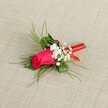A single-stem boutonnière lies gently on a softly textured, light beige fabric, the neutral background reminiscent of natural linen and allowing every detail of the flowers to stand out with clarity. At its heart is a tightly furled rosebud in a deep fuchsia, almost crimson-pink shade, the petals smooth and velvety, cupped together as if about to unfurl during a North Watford evening celebration. Around this central rose, clusters of tiny white baby's breath flowers form a delicate cloud, their minuscule blooms adding a lace-like softness that contrasts with the bold, saturated colour of the rose. Slender sprigs of bright green, feathery foliage, similar to asparagus fern or fine ruscus, fan out gracefully behind and around the bloom, giving the arrangement a sense of movement and airy lightness, like a gentle breeze over the lawns of Cassiobury Park. The deeper green leaves nestled at the base provide structure and depth, grounding the design. At the stem end, a slim, glossy red satin ribbon is wrapped neatly and firmly, binding the stems with a polished finish and creating a refined accent that echoes the rose's rich hue. The lighting is bright but soft, highlighting the natural sheen of the petals and ribbon without harsh shadows, and conveying freshness, care, and expert craftsmanship. This classic boutonnière, perfect for a groom, groomsman, or prom guest heading out from North Watford, captures the intimacy of special occasions-from registry office ceremonies to elegant hotel receptions-where a single rose on the lapel becomes a quiet yet powerful symbol of romance, promise, and personal style.