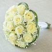 A high-angle, intimate view reveals an enchantingly classic bridal bouquet-crafted with expert skill right here in North Watford. At the core of the arrangement, ten to twelve creamy ivory roses, each a study in delicacy, cradle their spiral petals in close formation, signaling peak freshness and subtle grace. Sprays of baby's breath weave among the roses, their airy, cloud-like clusters lending a floaty, almost ethereal charm-reminiscent of a gentle morning over North Watford's leafy streets. Broad, deep green leaves curve around the blooms, introducing a vibrant pop of colour and a luscious, verdant contrast to the pale central flowers. The bouquet's stems are meticulously gathered and securely wrapped in pure white satin, creating a streamlined, elegant handle ready for a bride walking down the aisle at a nearby Watford venue. The bouquet rests on a softly textured, neutral background that allows every aspect of the design to shine. With its clean composition and understated sophistication, this arrangement eloquently expresses purity, romance, and elevated taste-making it a quintessential choice for weddings, milestone anniversaries, or heartfelt North Watford celebrations blessed by fresh flowers and thoughtful design.