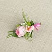 Softly illuminated and perfectly poised on a neutral, sand-colored linen backdrop, this boutonniere from a North Watford florist weaves together romance, artistry, and local flair. At its core, a pastel pink rose-each velvet-like petal coiled in a tight, graceful spiral-stands fresh and radiant. Nestled beside, a lighter-pink or muted peach flower, possibly Alstroemeria, displays open petals with sunlit yellow hints and faint, natural markings, creating visual intrigue. Cloud-like baby's breath and button-sized green cushion mums are thoughtfully placed, infusing airiness and a lively texture inspired by North Watford's springtime gardens. Lush greenery, ranging from slender blades to sculpted, folded dark leaves, provides structure and subtle drama, fanning upward like the branches of Oxhey Park's trees. The bundled stems are elegantly circled with a gleaming fuchsia pink satin ribbon, tied in a neat bow that gleams against the simple, rustic texture of the cloth beneath. Every element is arranged with the dedication and eye for beauty found in North Watford's floral workshops, resulting in a boutonniere that radiates gentle celebration and understated style-ideal for weddings, proms, or special occasions across the local community.