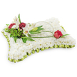 A lovingly crafted pillow-shaped sympathy cushion composed of hundreds of small, pure white chrysanthemums, photographed against a clean white backdrop so every textured petal reads like a soft, comforting quilt. The tiny chrysanthemum heads are tightly packed to create a cloud-like surface that invites the hand to rest and lingers with a suggestion of quiet warmth. Around the rectangular edge, a pleated pale lime-green satin ribbon has been folded with precision into a gentle frill, the satin catching a cool studio light and adding a subtle sheen that lifts the composition without overpowering it. Towards the upper left, the arrangement steps up into a natural cluster: two open white Oriental lilies, their trumpet shapes and faint honeyed perfume suggesting calm, stand alongside a closed lily bud ready to unfurl. Deep burgundy spray carnations nestle between the lilies, their ruffled petals providing rich contrast and a grounding, almost velvety shadow against the white field. Behind and between the blossoms, assorted green foliage - feathery fern fronds and broader salal leaves - creates depth and the feeling of a small, sheltered grove. From that left cluster a slender, arching loop of bright green bear-grass or salal leaf sweeps across the cushion like a graceful ribbon of living line work, and at its far right terminus rests a single deep red rosebud, just beginning to open, its velvety edge poised as a private sign of enduring love. As a local florist in North Watford I picture this tribute arriving gently at Cassiobury Park chapels or carried from a service on Watford High Street, offering quiet consolation and dignity.