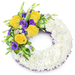 A solemn, hand-crafted 'O' shaped wreath rests against a clean white background, its circular form composed of hundreds of small, pristine white spray chrysanthemums tightly packed to create a smooth, cloud-like surface. The chrysanthemums' many layered petals give a soft, feathered texture that reads as purity and quiet comfort; the white surface appears almost luminous beneath soft studio light, inviting a gentle touch while conveying reverence. Along the upper left curve a vibrant, artful spray rises-several fully opened yellow roses, their butter-gold petals unfurling with a warm, delicate scent that suggests late summer sunlight. Nestled beside them are deep royal purple Eustoma (Lisianthus) with ruffled, cup-shaped blooms and a few slender, unopened buds in pale lavender and green that add natural depth and movement. Interwoven glossy, rounded foliage and lacy fern fronds form a verdant cradle for the blooms, the greens ranging from deep bottle green to softly variegated tones that lift the colourway and provide structure. A subtle trim of dark purple mesh or crinoline peeks from beneath the white chrysanthemum ring at both the inner and outer edges, a fine, lace-like detail that quietly ties the purple blossoms to the overall composition. The wreath's open centre and symmetrical silhouette make its intent evident: a respectful funeral or memorial tribute that balances purity with a comforting, hopeful accent. As a florist's piece suited for remembrance in North Watford-perhaps to be placed near a chapel or at a service by Cassiobury Park-the arrangement holds a composed dignity, conveying sympathy, fond memory, and a gentle farewell.