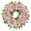 Set against a crisp white background, this circular sympathy wreath forms a complete, unbroken ring of soft colour and gentle texture, much like a comforting embrace offered at a North Watford farewell. The design is lavish with roses, the main blooms opening wide in shades of dusty lavender, antique mauve, and subtle greyish-purple, each petal curving inwards to create lush, layered rosettes. These larger flowers are thoughtfully spaced around the wreath, and between them, clusters of blush-pink spray roses weave through the ring. Some of these smaller roses are tightly closed, others half-open, their petite petals giving the arrangement a delicate, almost whispered quality, as though capturing both memories and unspoken goodbyes. Underpinning the flowers is a dense bed of dark green fern fronds, likely leatherleaf or sword fern, whose feathered, serrated leaves flare outward and provide both support and a rich, natural frame. The contrast between the verdant greens and the pastel rose tones creates a harmonious balance that feels both fresh and quietly dignified, reminiscent of a calm walk through North Watford's green corners on a still day. Tiny, darker buds and subtle filler foliage tuck into spaces between the blossoms, adding depth and shadow that make the wreath appear full and three-dimensional. The lighting is even and soft, revealing details in every petal and leaflet, and enhancing the sense of serenity. Intended as a funeral or memorial tribute, this wreath expresses sympathy, remembrance, and gratitude, the lavender and pink roses symbolising grace, admiration, and the enduring love held for someone deeply missed.