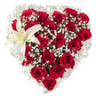 A lovingly shaped heart of flowers sits against a crisp white background: dozens of deep crimson red roses are packed closely together to form a rich, velvety silhouette, their petals ranging from tight, jewel-like buds to fully unfurled blooms that catch soft morning light. Tiny, star-like clusters of white baby's breath (Gypsophila) are woven generously through the roses, creating a feathery, cloud-like texture that breathes lightness into the dense red and softens the heart's outline. In the upper-left curve a single, sculptural white lily opens proudly - its broad, pure-white petals edged with the faintest hint of cream and a warm yellow at the throat, where slender yellow stamens lend a small, sunlit accent. The contrast of textures - the velveteen rose petals, the airy gypsophila, and the smooth, waxy lily - invites both sight and memory of scent: heady, classic rose perfume tempered by the cleaner, green note of the lily.

Crafted with precise shaping and quiet restraint, this arrangement reads as a heartfelt declaration: romantic and refined, ideal for anniversaries, Valentine's gestures, or as an elegant tribute. As a local florist familiar with North Watford and nearby Cassiobury Park, I picture this sitting on a mantelpiece after a walk through the avenue of trees, or sent from Watford High Street to a loved one who deserves something timeless. The white background isolates the design so every fold and shadow is visible - a study in love made tangible by experienced hands and fresh blooms sourced the same day wherever possible in North Watford.