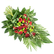 An elongated, crescent-like funeral spray lies against a clean white backdrop, its form sweeping from a tall, structured cluster at the upper left down into a slender, gently pointed tip at the lower right. The central focus is a dense gathering of deep red flowers: classic roses with velvety petals, some fully open in generous spirals and others still in promise as buds; striking red gerbera daisies with darker inner discs; and frilled carnations that soften the lines between each bloom. Woven through this sea of crimson, rounded lime green chrysanthemum pompons create a vivid contrast, their fresh, almost neon green adding a modern brightness that lifts the mood of the tribute. Here and there, delicate white filler flowers - perhaps tiny daisies or airy gypsophila - peek out between leaves and petals, providing light, almost cloud-like touches that keep the composition from feeling too dense. A rich frame of foliage surrounds everything: broad, glossy dark green leaves forming a strong foundation, complemented by light, feathery ferns and other textured greens that give depth and movement. At the base on the right, several long, smooth, strap-like green leaves are fanned outward, reinforcing the spray's directional line. At the top left, a small bundle of straight green stems stands upright, secured by a single broad leaf wrapped neatly around them for a refined, designer finish. Crafted in a style familiar to local North Watford florists providing funeral flowers, this arrangement feels both solemn and vibrant, suitable as a casket spray or standing tribute for a North Watford memorial or cremation service, expressing respect, remembrance, and enduring affection.